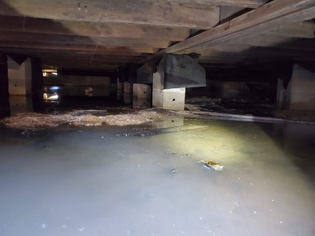 Standing water in a flooded crawl space after a Richmond storm