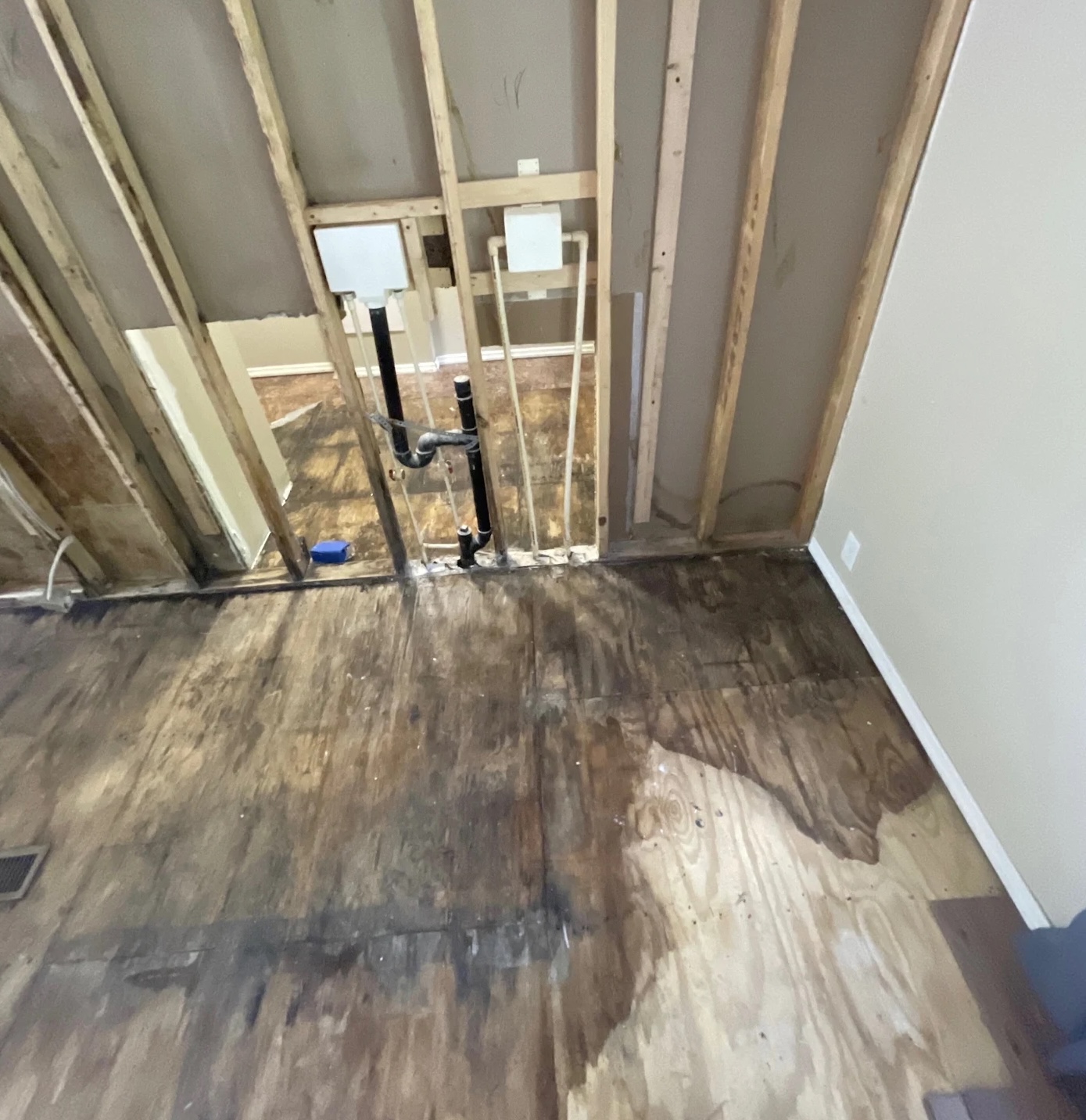 Exposed subfloor and wall studs after water damage extraction in Richmond